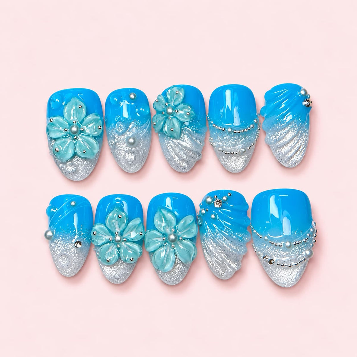 Azure Shell short almond press-on nails in bright blue fading to silver glitter with sculpted mint flowers and bead strands