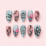 Candy Swirl almond press-on nails in baby blue and pink stripes with raised silver swirls, flowers and studs