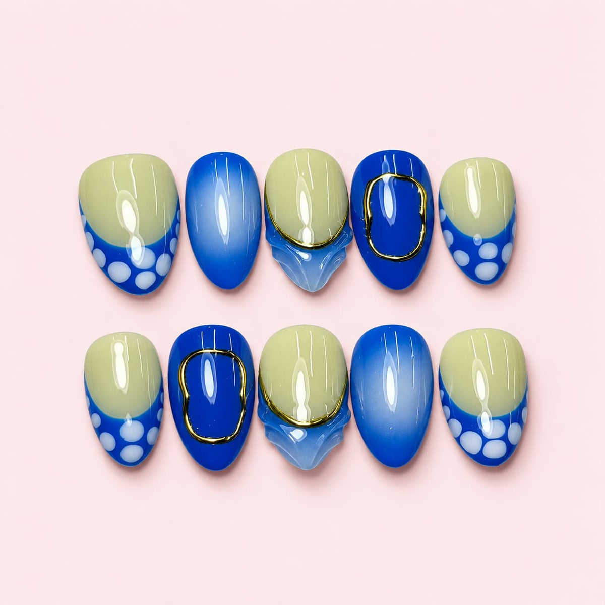Cobalt Dot short almond press-on nails in cobalt blue and pale sage with white dots and gold-toned frames