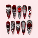 Crimson Relic stiletto press-on nails in deep oxblood red with silver-toned hearts, baroque frames and dark red stones