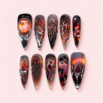 Ember Drift stiletto press-on nails in black and burnt orange with silver-toned flame work and a fiery opal-effect stone