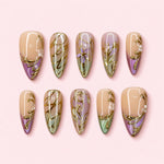 Gilded Iris almond press-on nails in nude lavender and sage with raised gold irises, leaves and scrolling vines