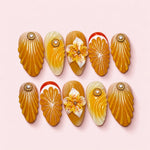 Honey Shell almond press-on nails in amber and mustard with deeply carved shell ridges and a sculpted speckled lily