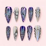 Iris Armour stiletto press-on nails in violet and pearl white with silver tribal line work and sculpted ridges