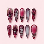 Neon Orchid stiletto press-on nails in burgundy and smoke with sculpted orchids outlined in neon pink