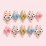Nude cow print almond press-on nails with colorful 3D bead accents