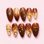 Terracotta Sun almond press-on nails in rust and cream with raised gold suns, moons, stars and flowing lines