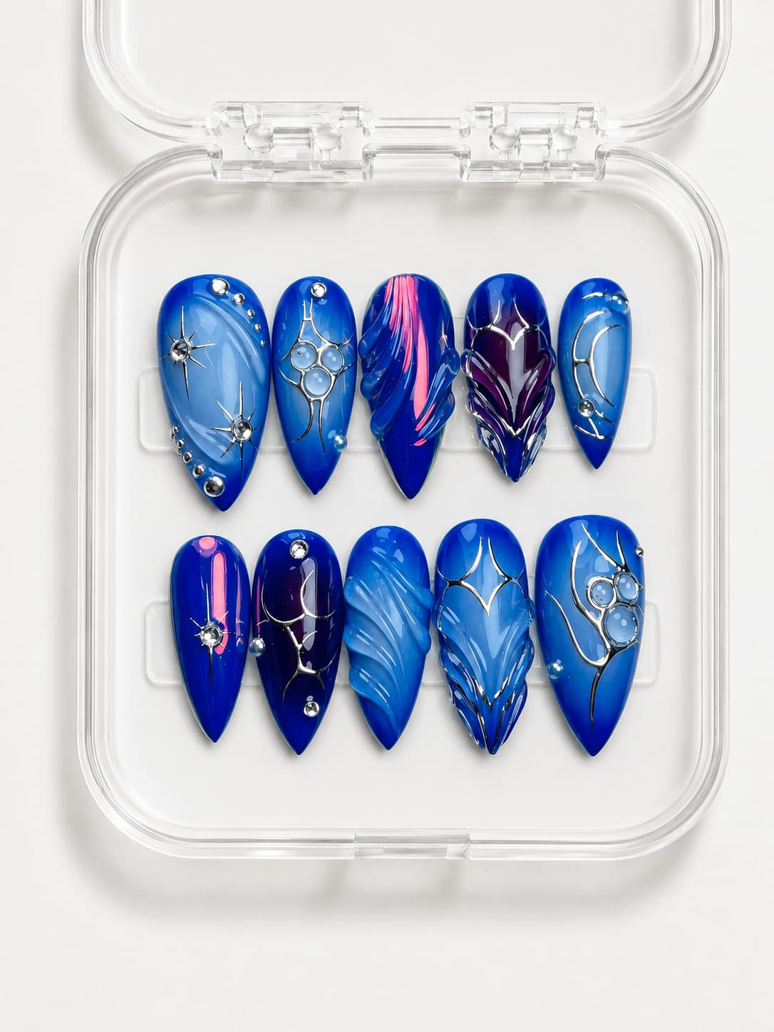 Cobalt blue stiletto press-on nails with silver swirls, color-shift accents, gemstones, stars, and 3D gel bubbles.