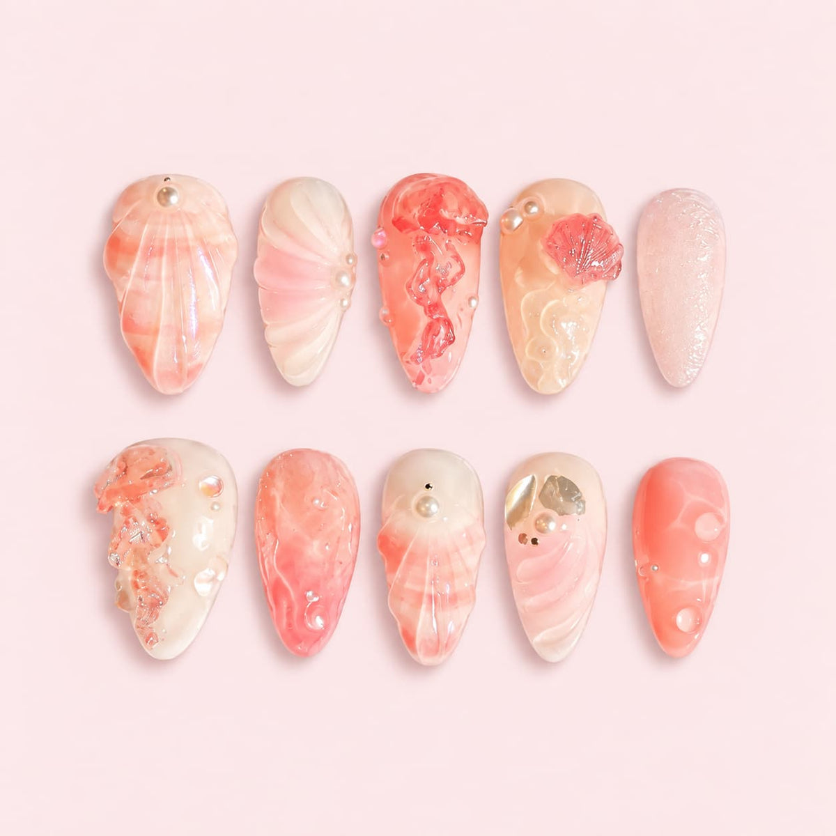 Coral pink long almond press-on nails with 3D seashells, pearl accents and water-drop details