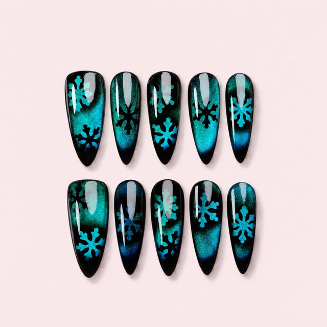 Emerald Cat Eye Snowflake Stiletto Press-On Nails with teal-blue magnetic glow, deep black edges and hand-painted snowflake designs.