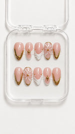 Gold French tip almond press-on nails with 3D white flower, star charms, pearl and gemstone accents