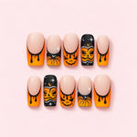 Halloween Pumpkin French Press-On Nails with orange dripping tips, hand-painted jack-o'-lanterns and black sparkle accent nails.