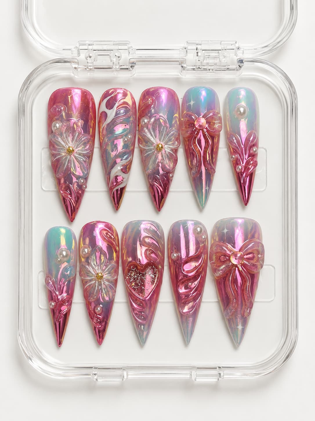 Pink aura stiletto press-on nails with teal color-shift accents, 3D flowers, bows, hearts, pearls, and gemstones.