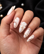 Hand wearing pink pearl chrome nails with iridescent milky pink shine, pearl embellishments, 3D bow, and raised white wave details.