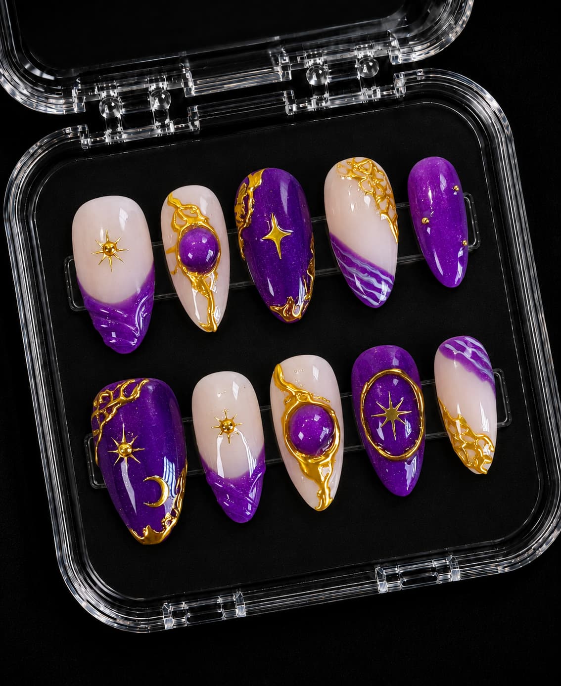 Purple and nude short almond press-on nails with gold sun, moon and star accents, molten frames, and purple gel domes.