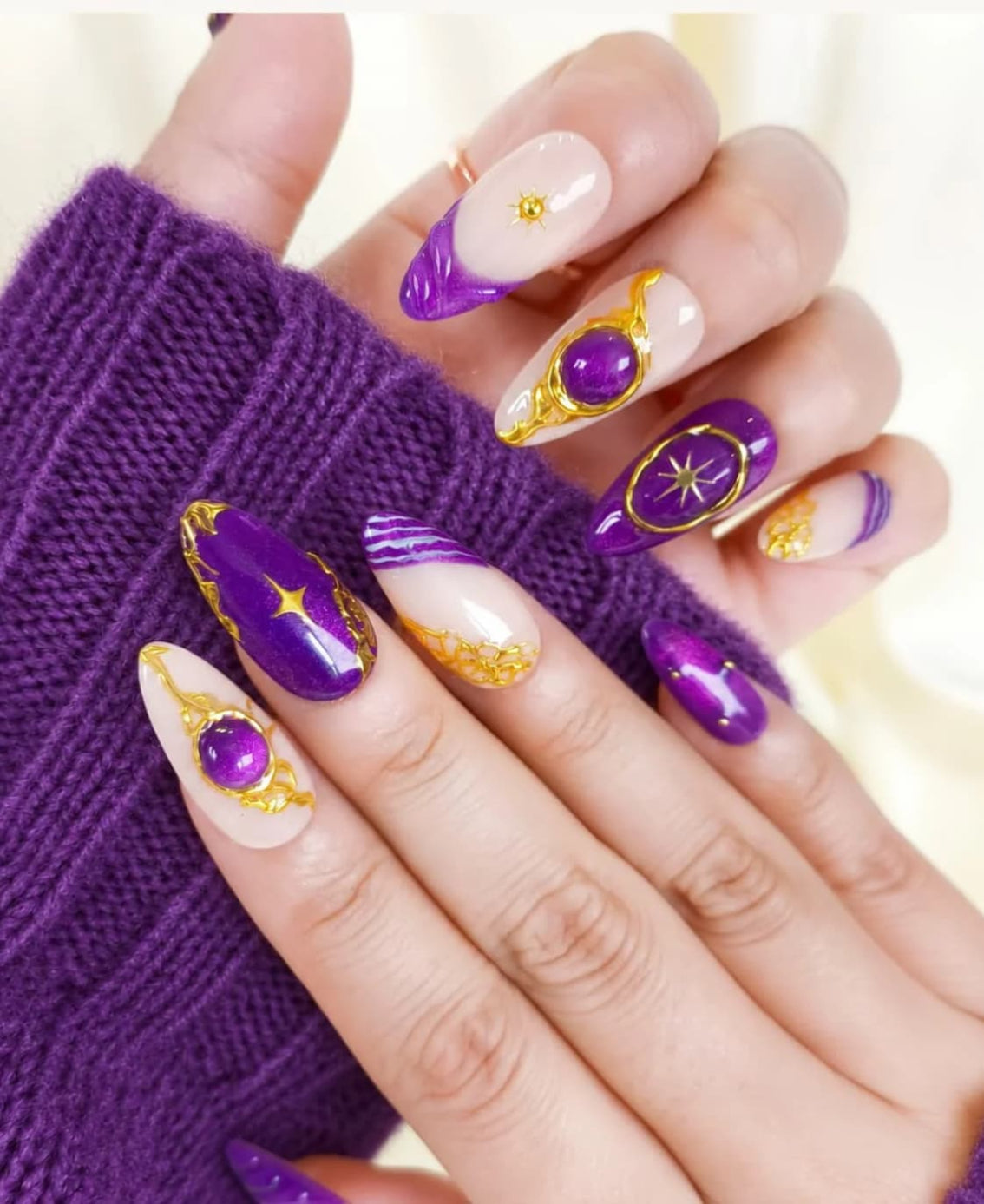 Short purple French tip press-on nails with gold celestial details and nude base